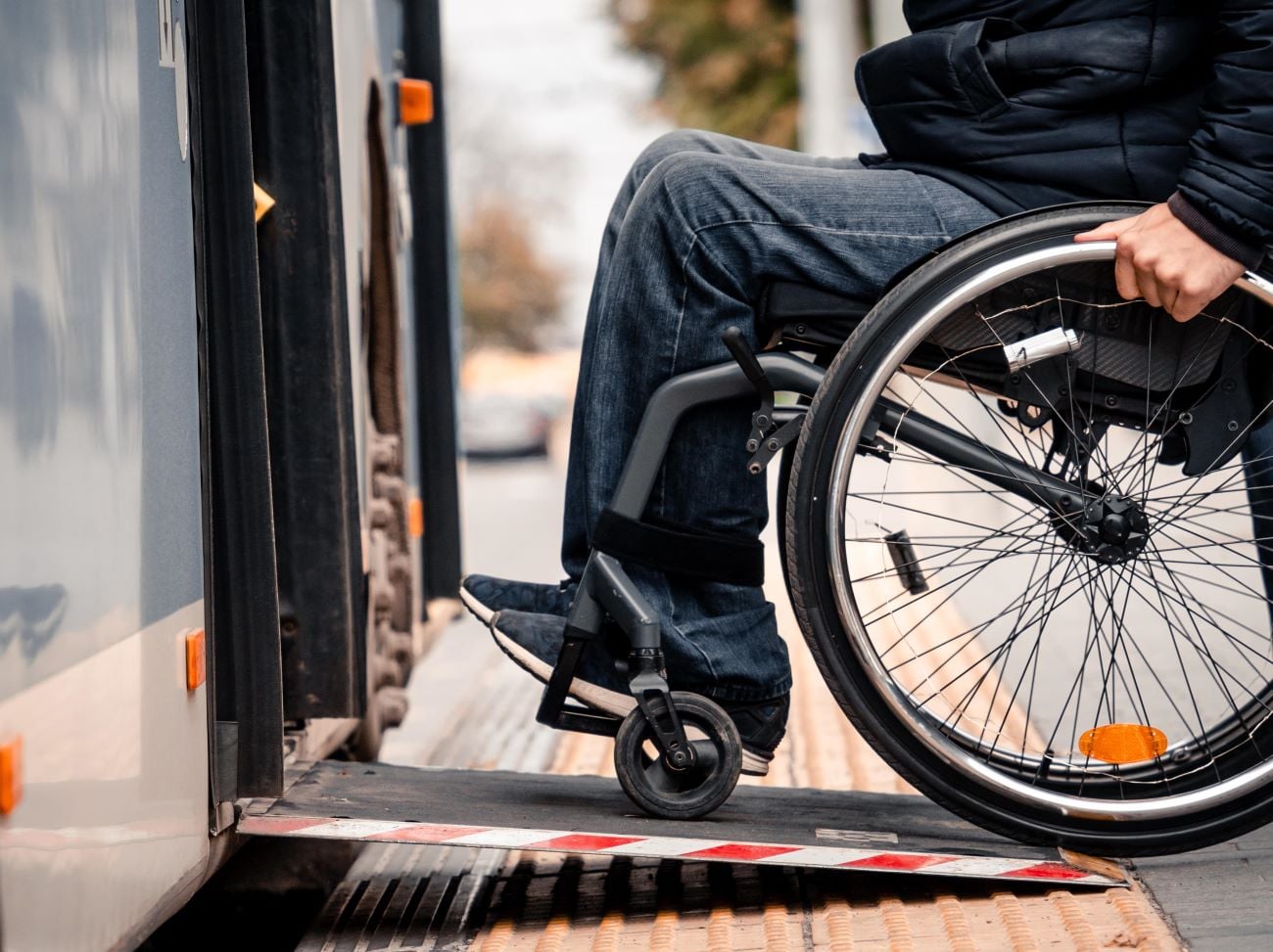 Person with a physical disability enters public transport with an accessible ramp.