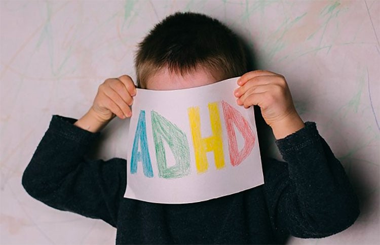 Boy holding sheet of paper with ADHD letters on it