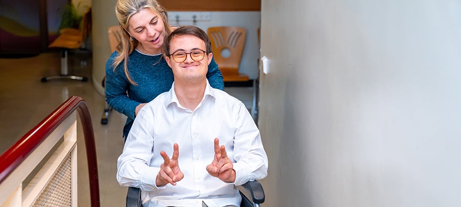 Young man sitting in a wheelchair giving a thumbs up sign