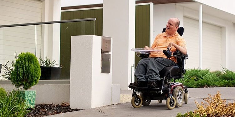 Man in wheelchair outside house