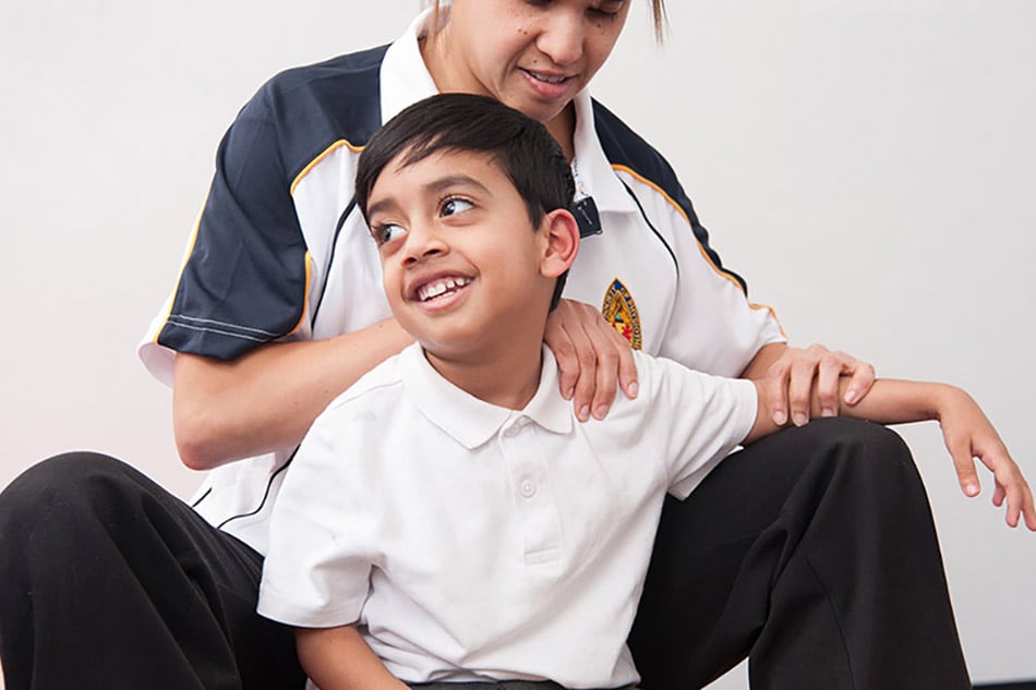 A physiotherapist working with a young boy with cerebral palsy
