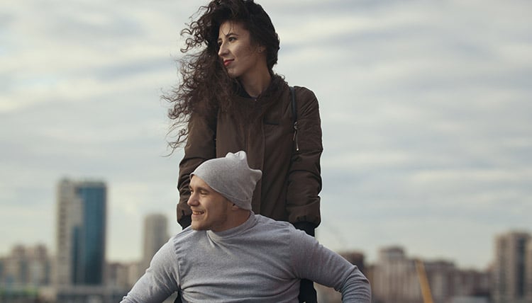 Woman standing behind her partner who is in a wheelchair