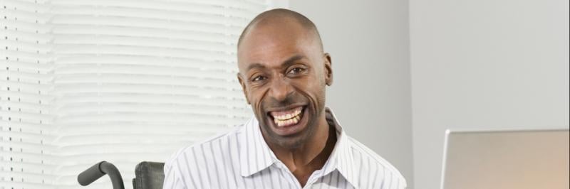 Man sitting in a wheelchair smiles widely