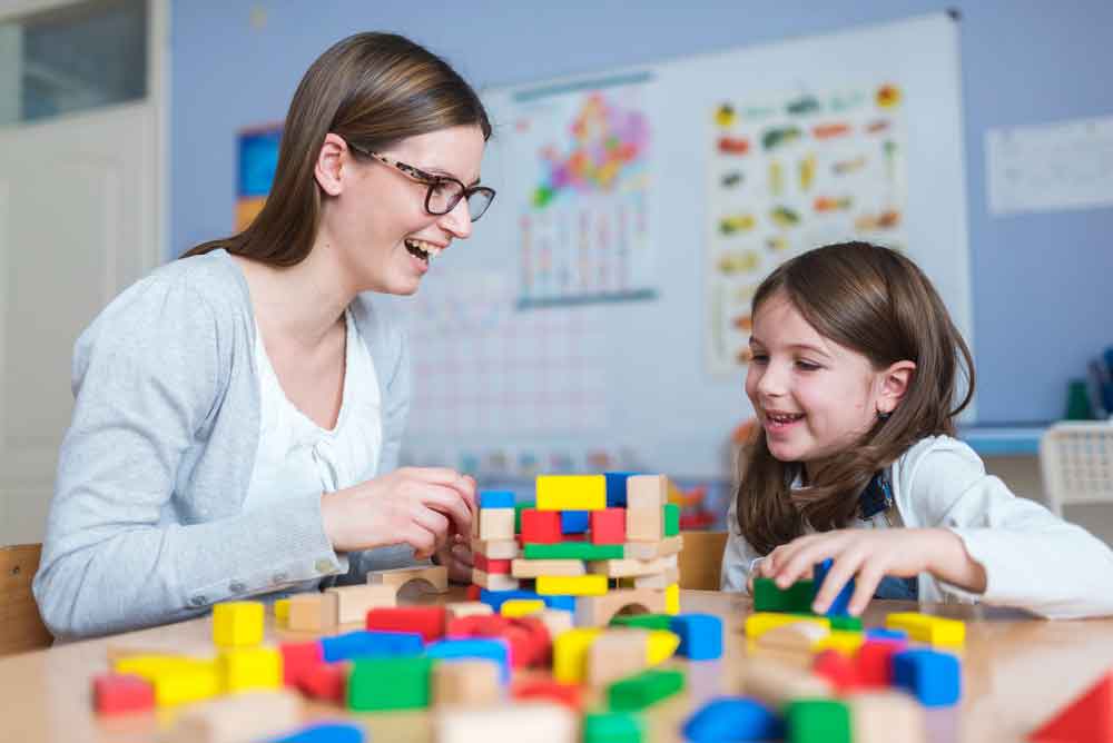 An NDIS OT with a child using large lego blocks on MyCareSpace