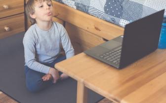 kid with speech delay sitting infront of a laptop attending online speech therapy
